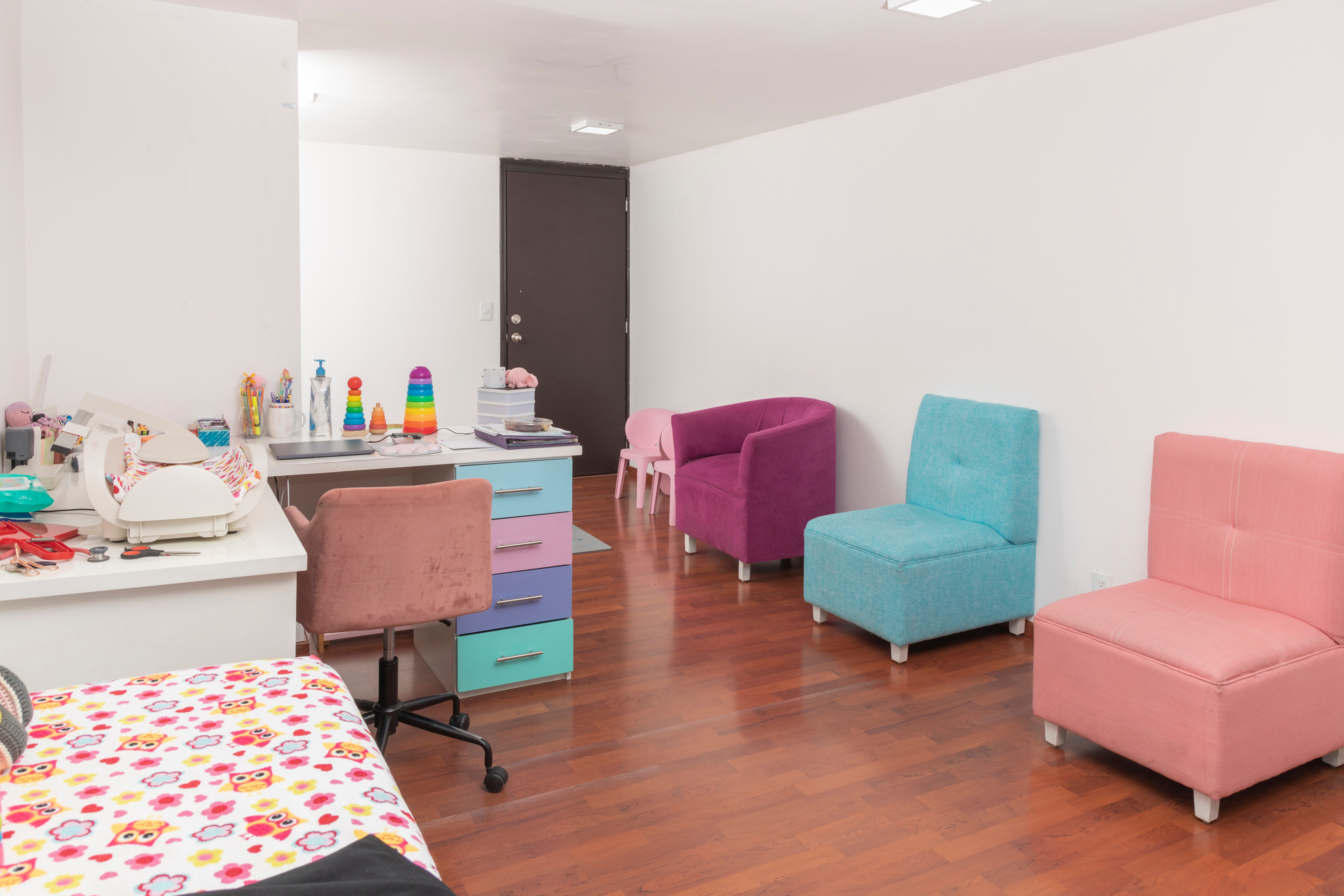 Colored armchairs in the waiting room of a pediatric office, with the desk next to it